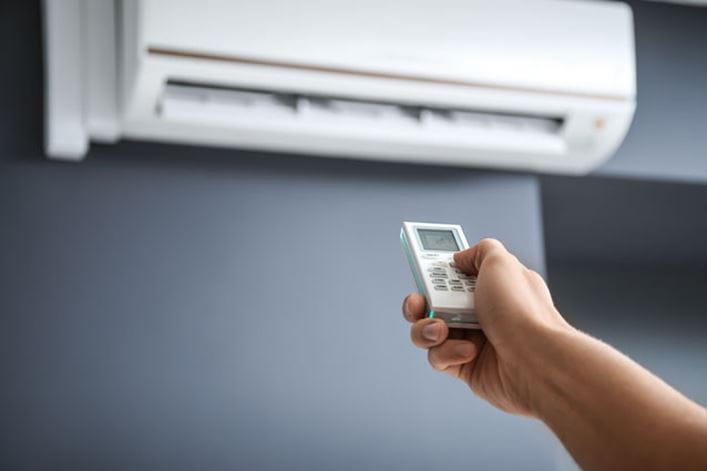 Mando de aire acondicionado en modo DRY en la mano de un técnico de aire de HomeServe