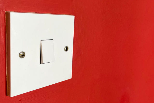 Interruptor simple de color blanco en la pared roja de una casa