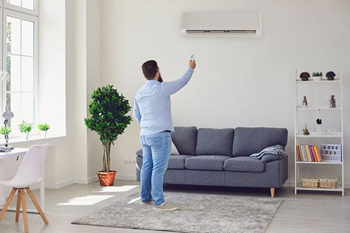 Hombre mirando un aparato de aire acondicionado que hace ruido