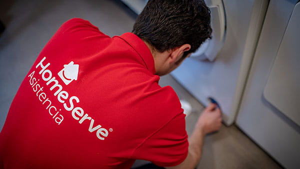 Técnico de reparación de lavadoras de HomeServe arreglando una lavadora que hace mucho ruido al centrifugar