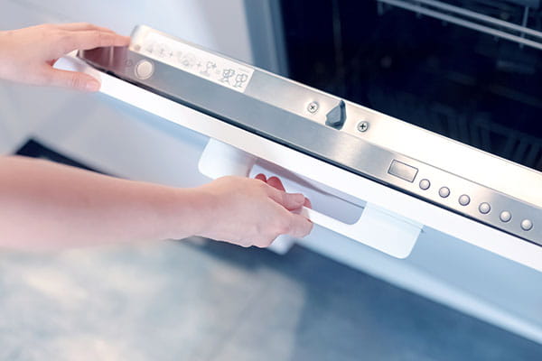 manos de mujer reseteando un lavavajillas